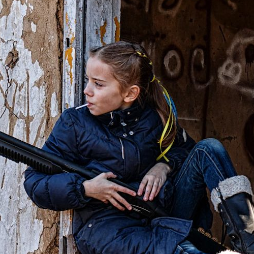 Bambina ucraina con lecca-lecca e fucile, la foto simbolo della guerra. A scattarla il padre