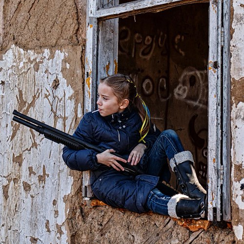 Bambina ucraina con lecca-lecca e fucile, la foto simbolo della guerra. A scattarla il padre